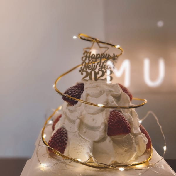 Studio Multisweet's New Year 2023 dessert, a whipped cream cake with strawberries and fairy lights.