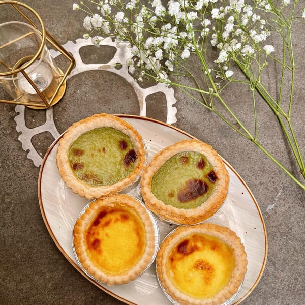 Four Studio Multisweet tarts, two green and two yellow, on a plate with baby's breath flowers.