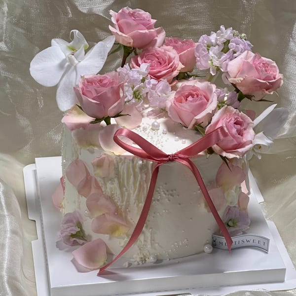 Studio Multisweet dessert cake with pink roses, white orchids, and a pink ribbon.