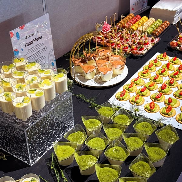 A dessert buffet with various small treats, including tiramisu, green grape milk pudding, and matcha desserts.