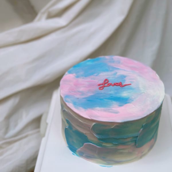 A Studio Multisweet cake with blue, pink, and white frosting, and the word "Love" on top.